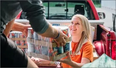 a person being handed packs of canned food