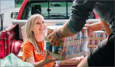 a person being handed packs of canned food