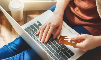 Woman holding credit card by laptop