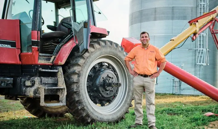 man smiling standing in front of a tractor