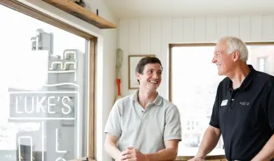 Two man standing by a table smiling