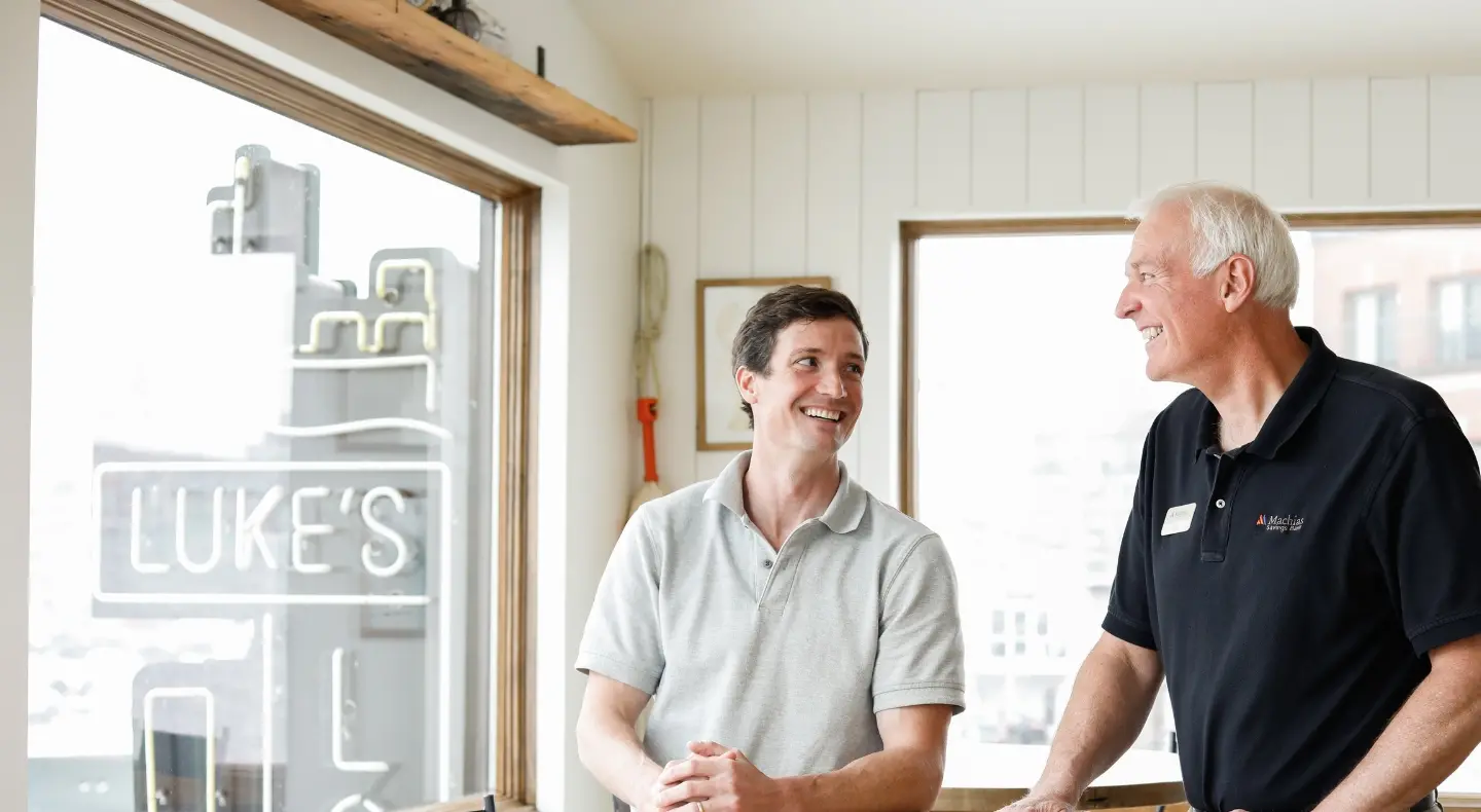 Two men standing by a table smiling