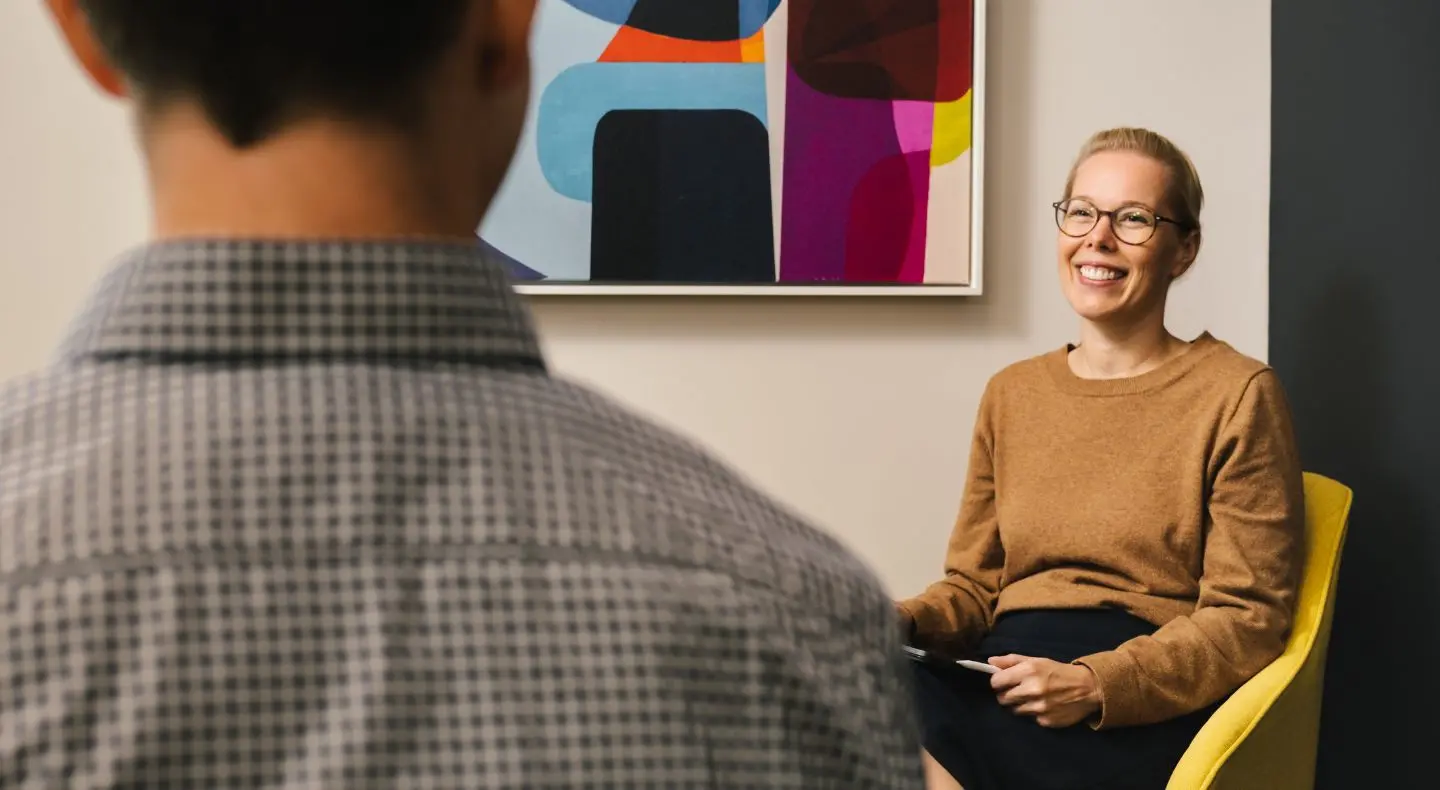 a woman engaged in conversation with a person and smiling