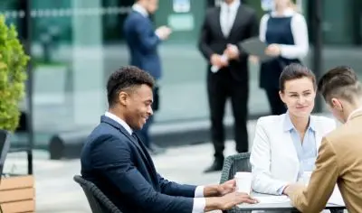 three business-people talking outside at a table