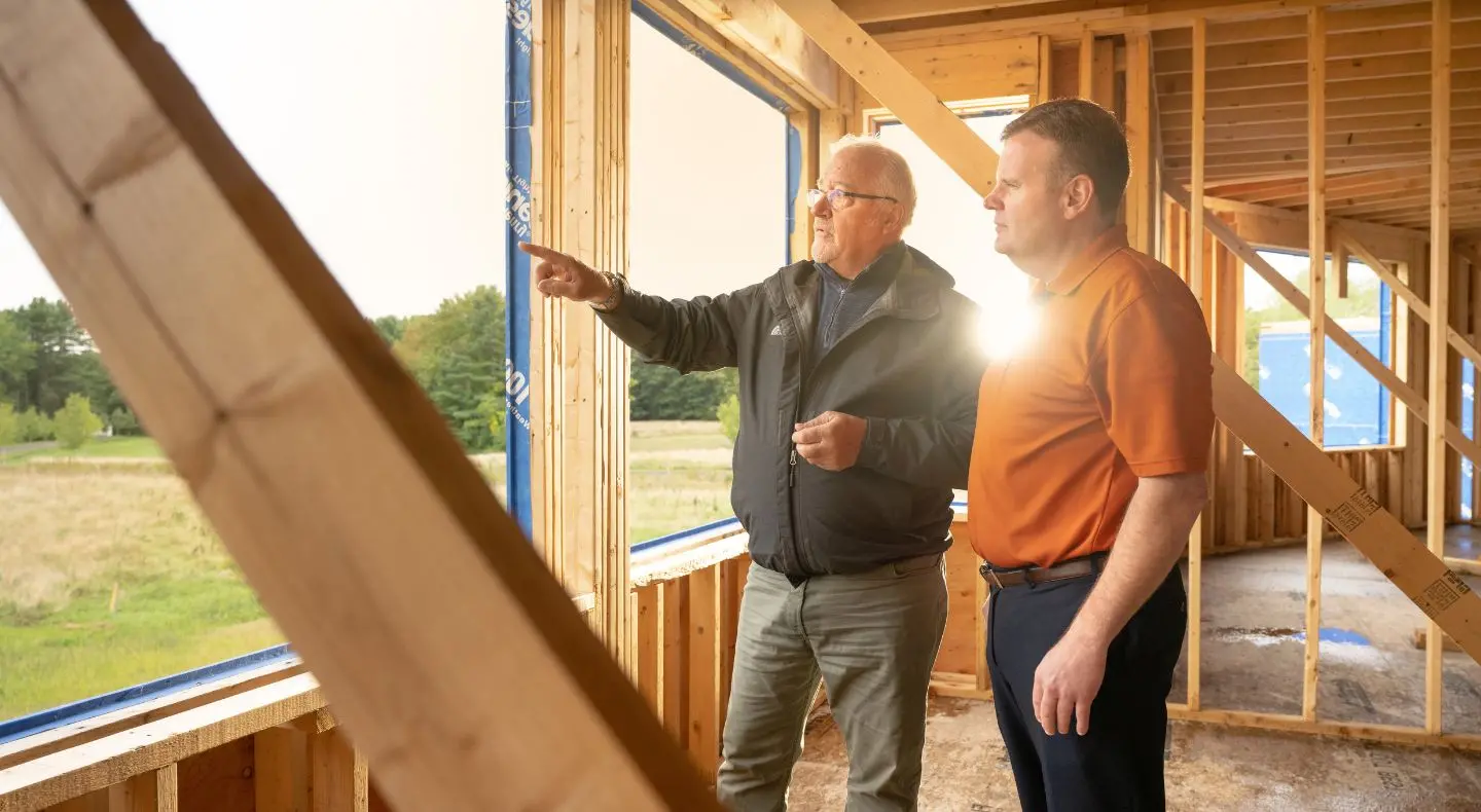 two people in a building under construction, looking out the window