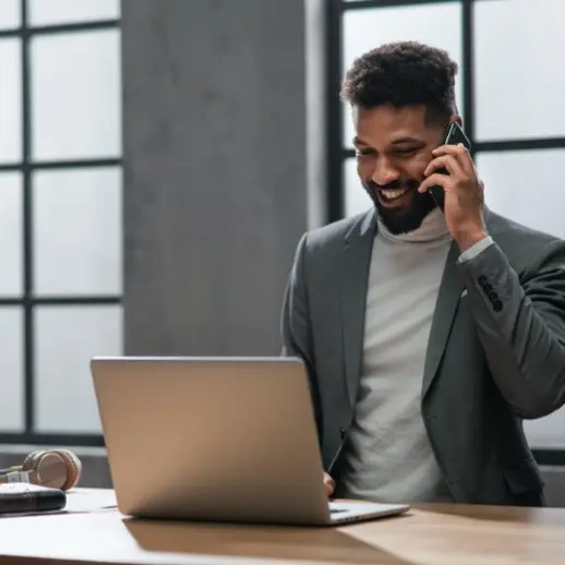 a smiling man, dressed in professional attire, looking at a laptop