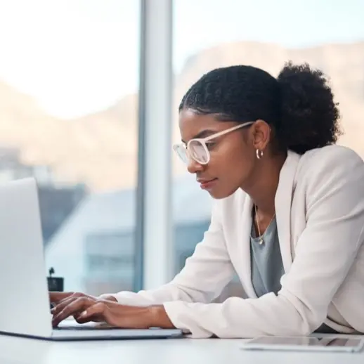 a woman wearing glasses, typing at a laptop computer