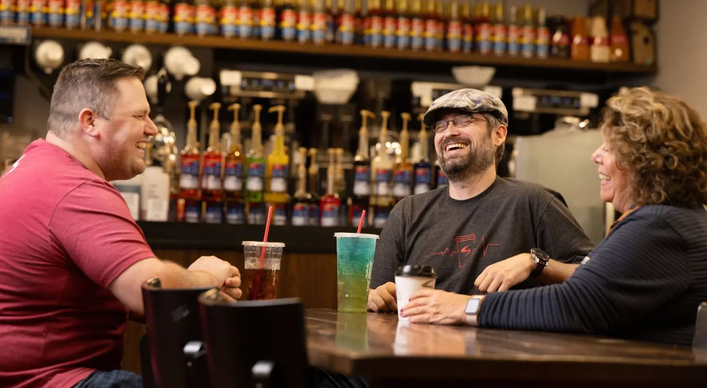 three people smiling at table