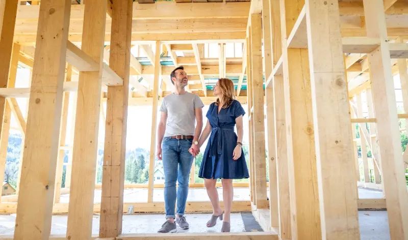 a couple holding hands, walking through a building under construction