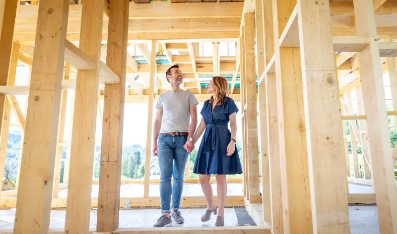 a happy couple holding hands, walking through a building under construction