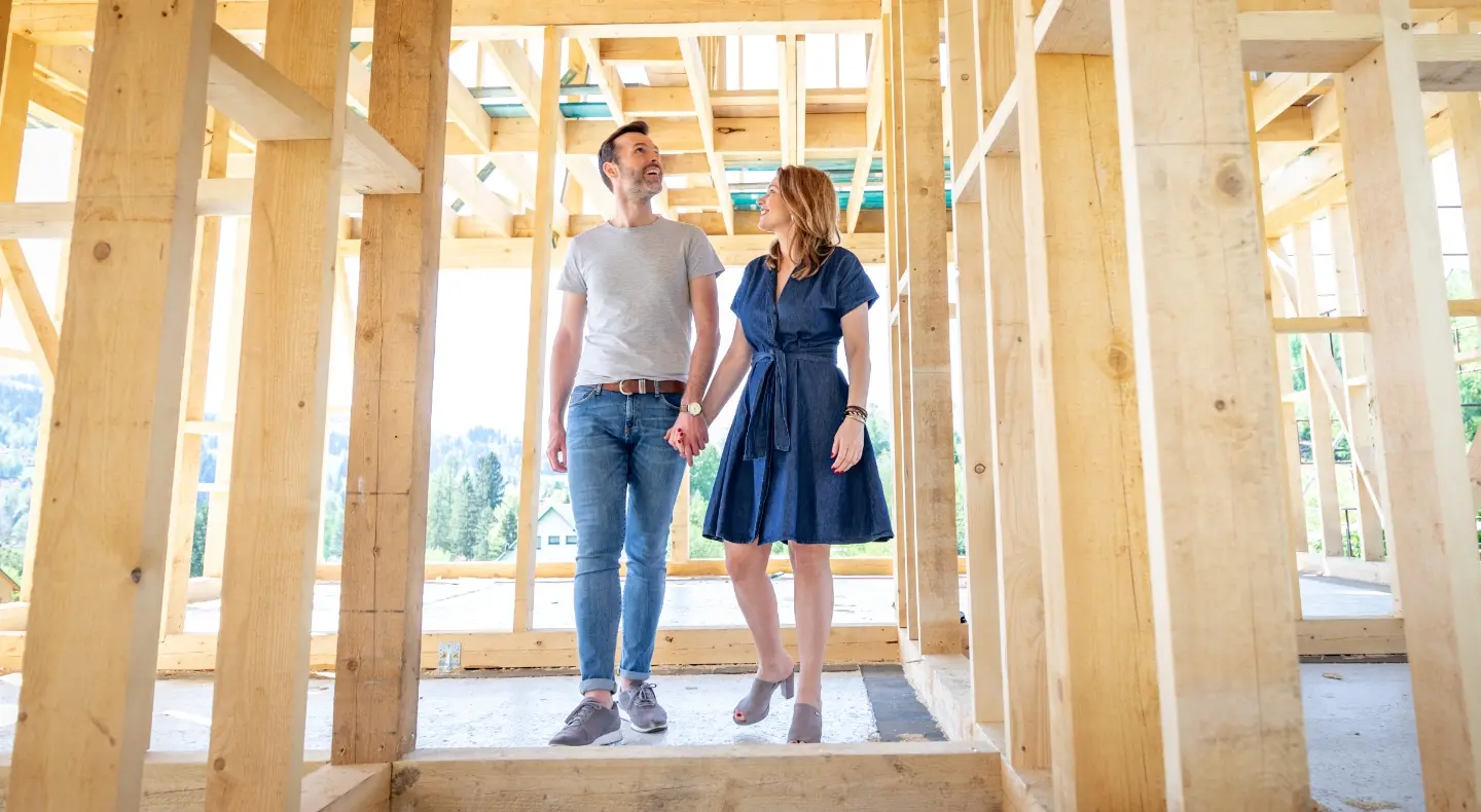 a happy couple holding hands, walking through a building under construction