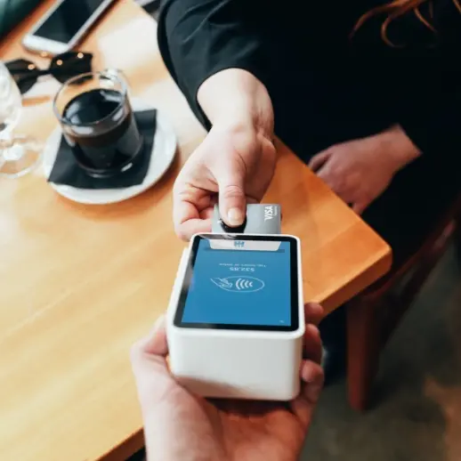 woman paying for coffee with credit card on mobile payment machine