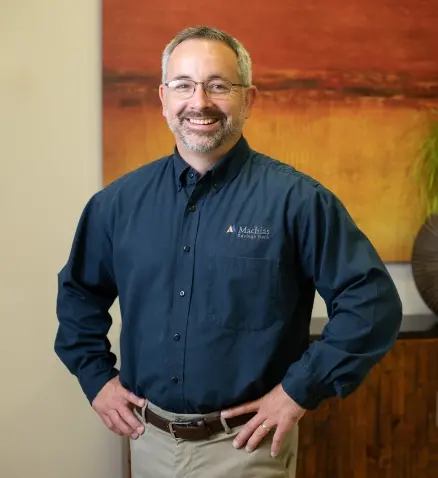 a man standing in a bank with glasses on and a dark blue shirt