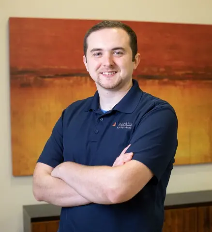 smiling man in a bank, with a dark blue collard shirt on