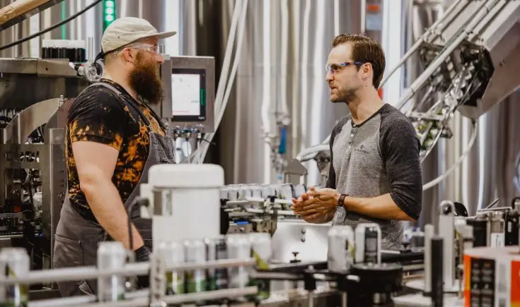 two men talking in a manufacturing building