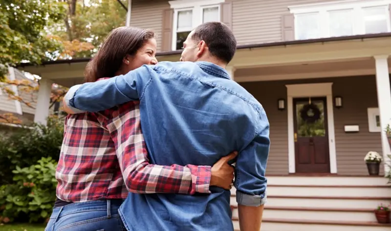 a happy couple walking towards a modern home