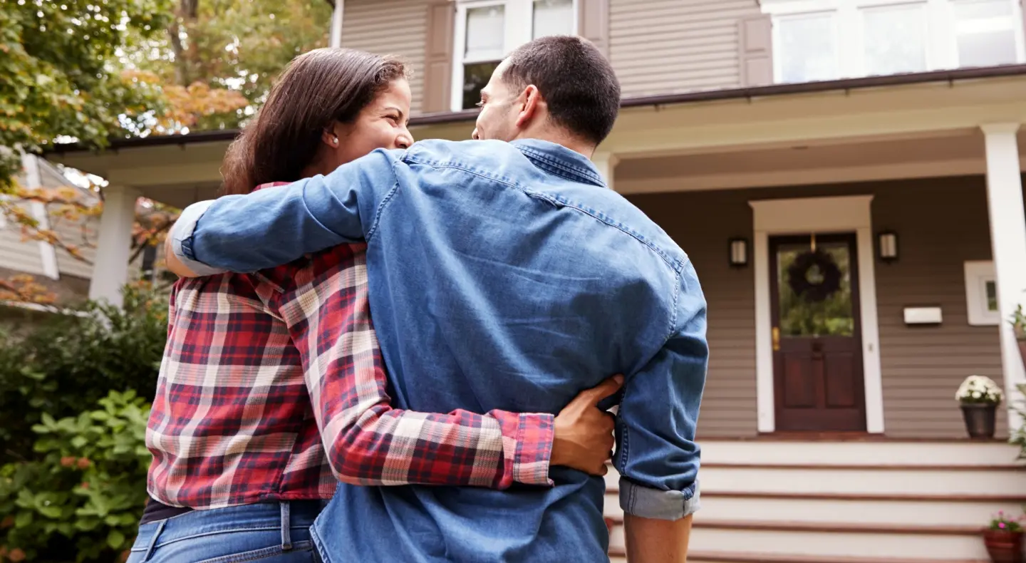 a happy couple walking towards the front door of a modern home