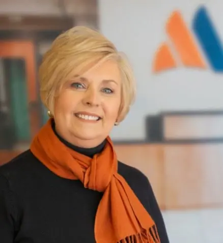 a headshot of a woman smiling, wearing an orange scarf