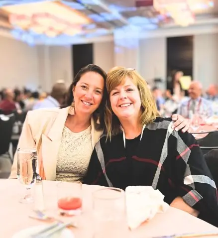 two people sitting down at an event, posing for a picture