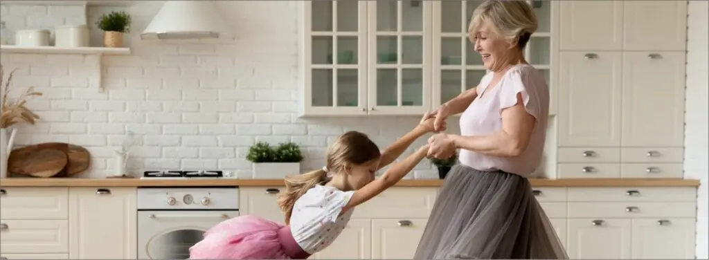 Grandmother dancing with granddaughter in kitchen
