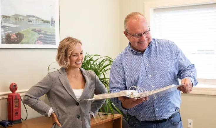 man and woman smiling looking at binder full of papers