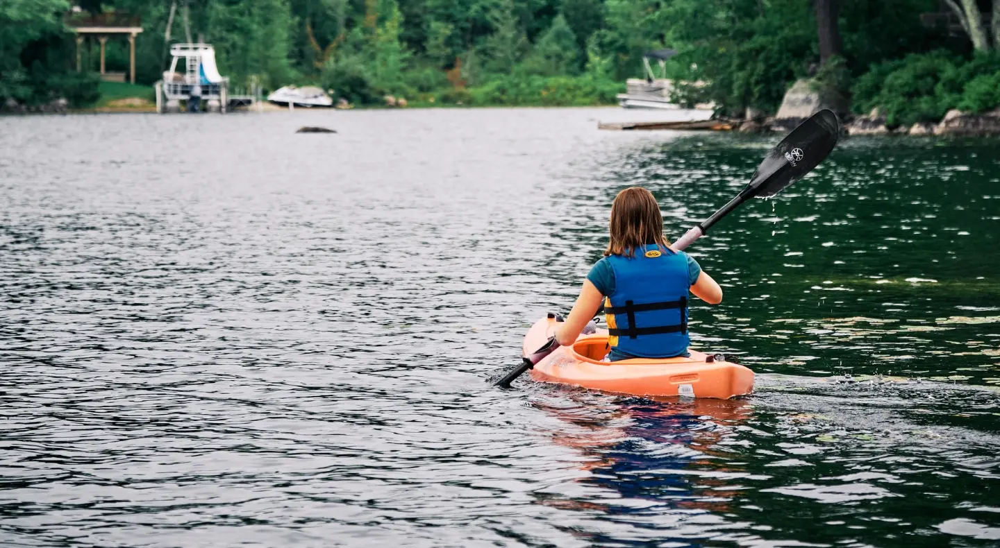 Young girl paddling a kayak in a lake