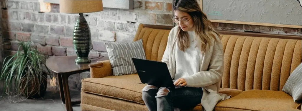 a woman sitting on a couch, holding a laptop