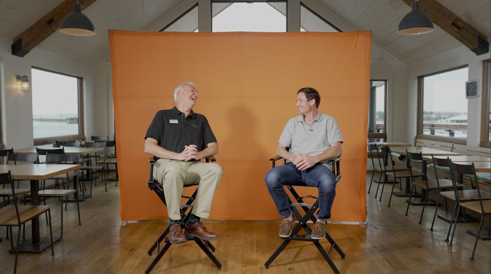 Two men in front of orange background