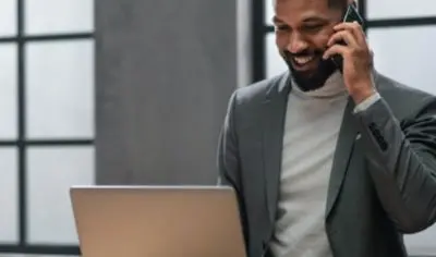 a man dressed in professional attire, smiling at a computer