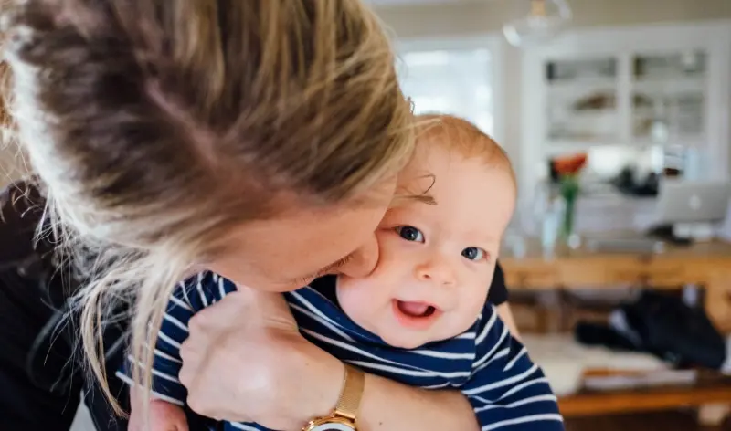 a mom kissing her baby on the cheek