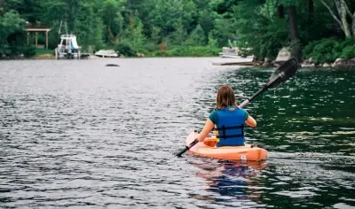 Young girl paddling a kayak in a lake