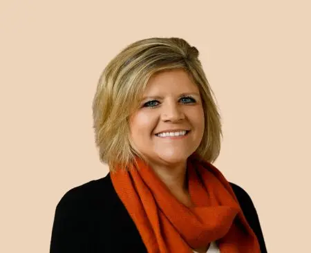 woman smiling wearing black top and orange scarf