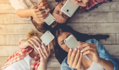 four people laying on the ground looking at their phones