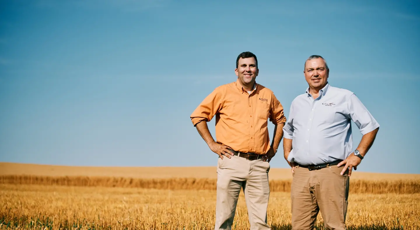 Two business men standing in a field smiling