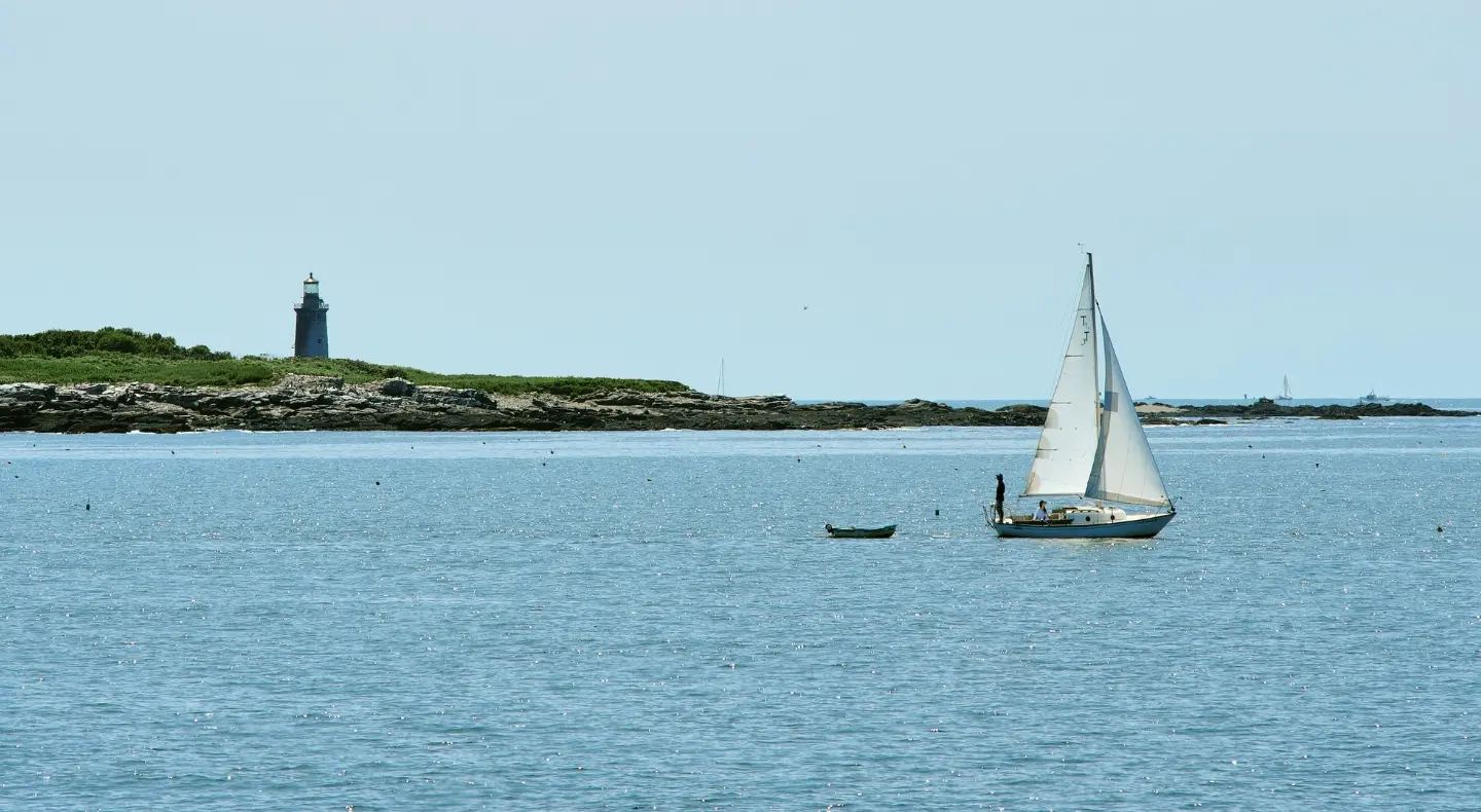 Sailboat in front of island with lighthouse