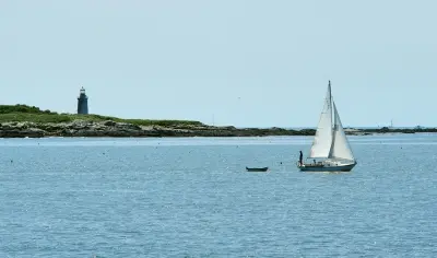 Sail boat in front of island with light house