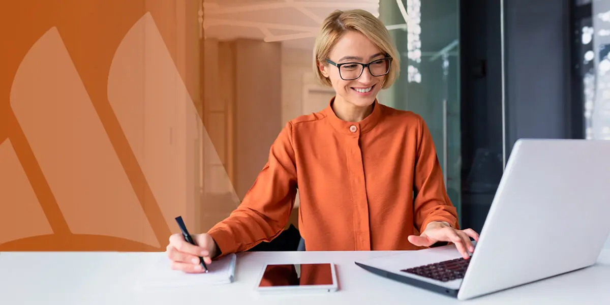 person looking at a laptop and taking notes