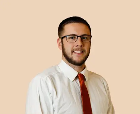 man smiling wearing white button-up shirt with orange tie