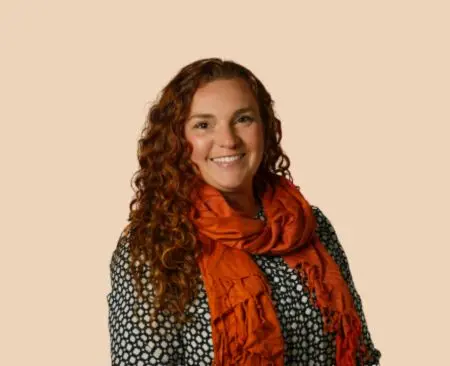 smiling woman with curly hair in a black and white polka dot blouse with an orange scarf