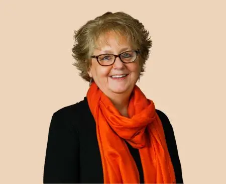 woman smiling wearing a black top with orange scarf