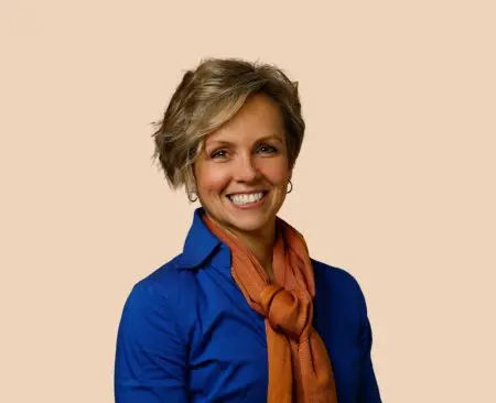 woman smiling wearing blue button-up top and orange scarf