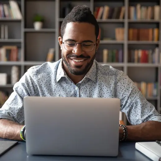person using a laptop at a desk in front of bookshelves