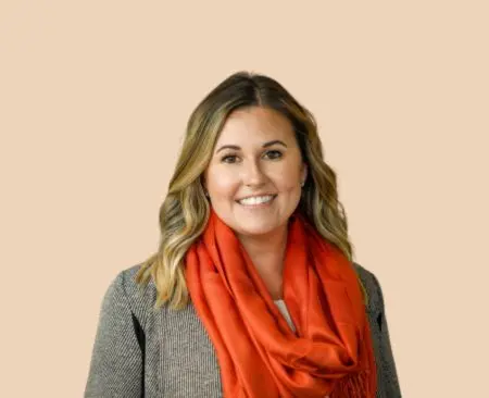 smiling woman with blonde hair in a gray blouse and an orange scarf