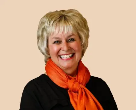 woman smiling wearing a black top with orange scarf