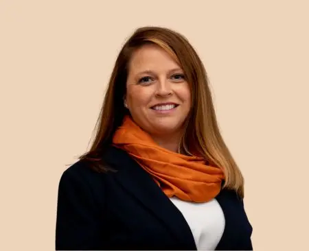 woman smiling wearing black suit jacket over a white top with orange scarf