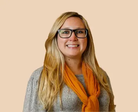 woman smiling wearing gray top and orange scarf