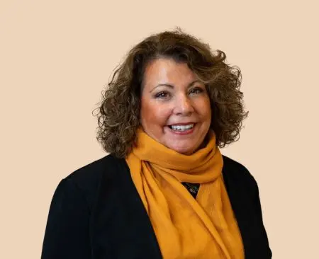 woman smiling wearing black top and orange scarf