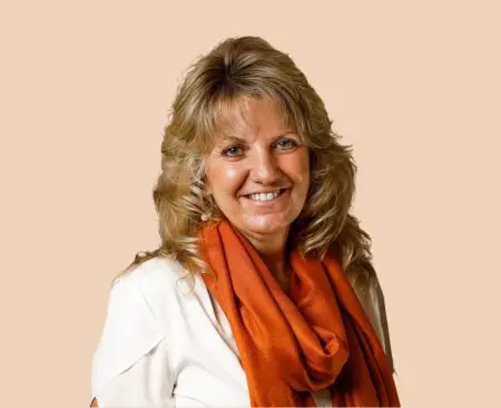 woman smiling wearing a white top with orange scarf