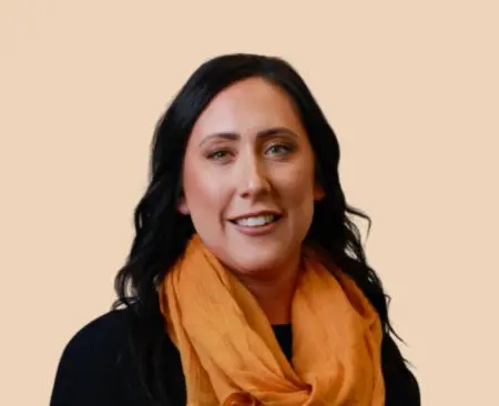 smiling woman with dark wavy hair in black blouse with an orange scarf