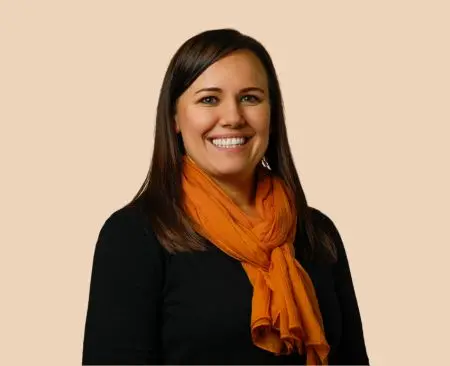 woman smiling wearing a black top with orange scarf